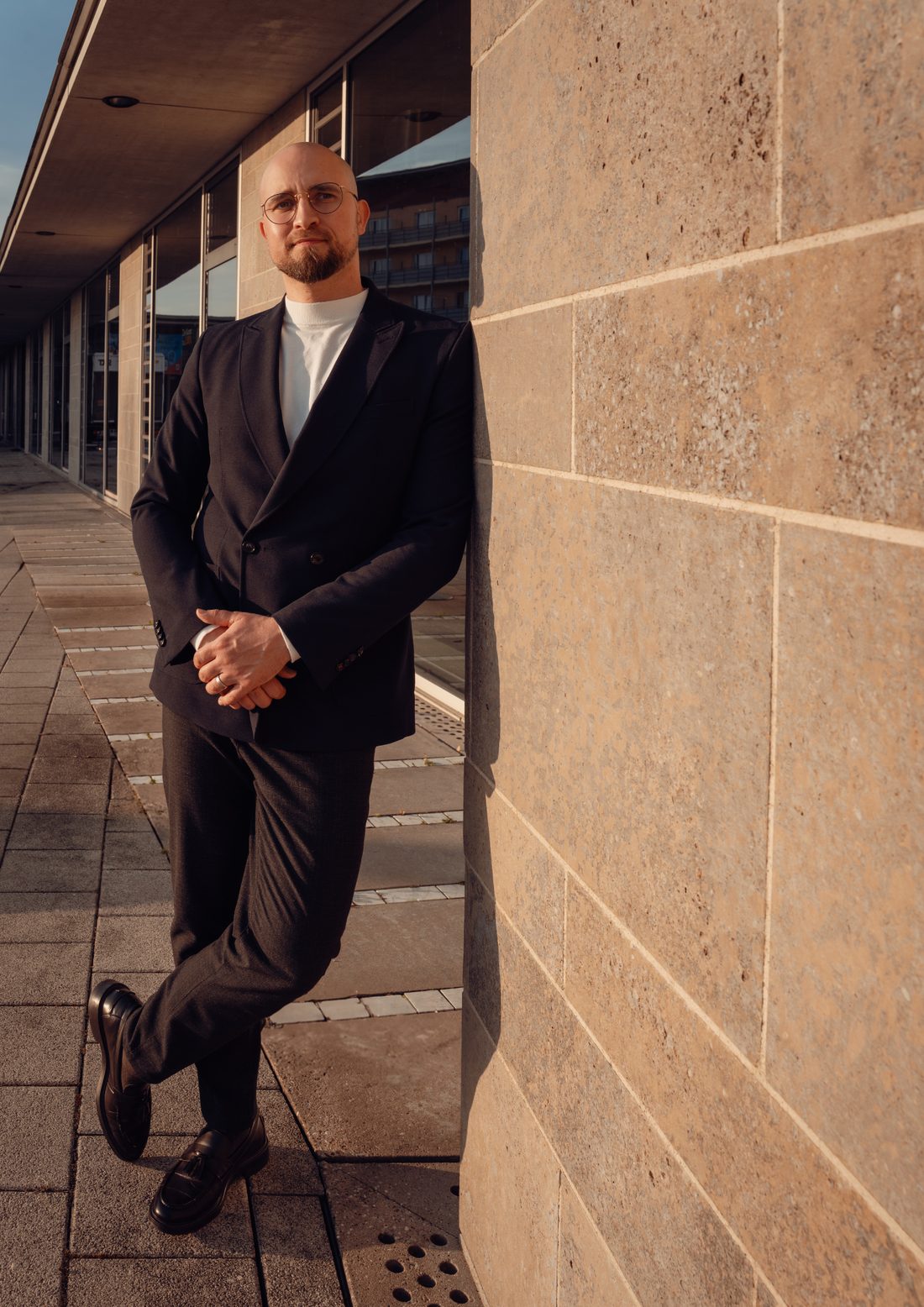 Bastian Kapfenberger, Kapitalstratege, im dunklen Anzug an einer Steinfassade